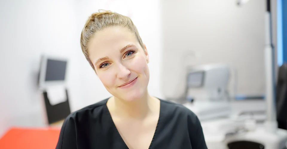Lächelnde Augenärztin in moderner Praxis zum Faktencheck über den Mythos, dass sich Augenärzte nicht selbst lasern lassen.