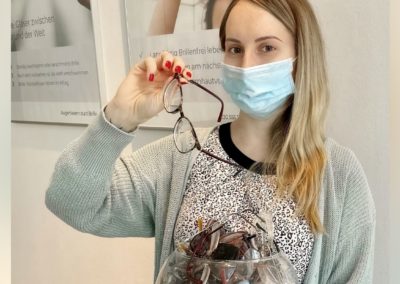 Junge Frau wirft ihre Brille in ein Glas zur Brillenspende nach der Femto-Lasik Augenlaserbehandlung im Augenlaser-Zentrum in der Schönhauser Allee