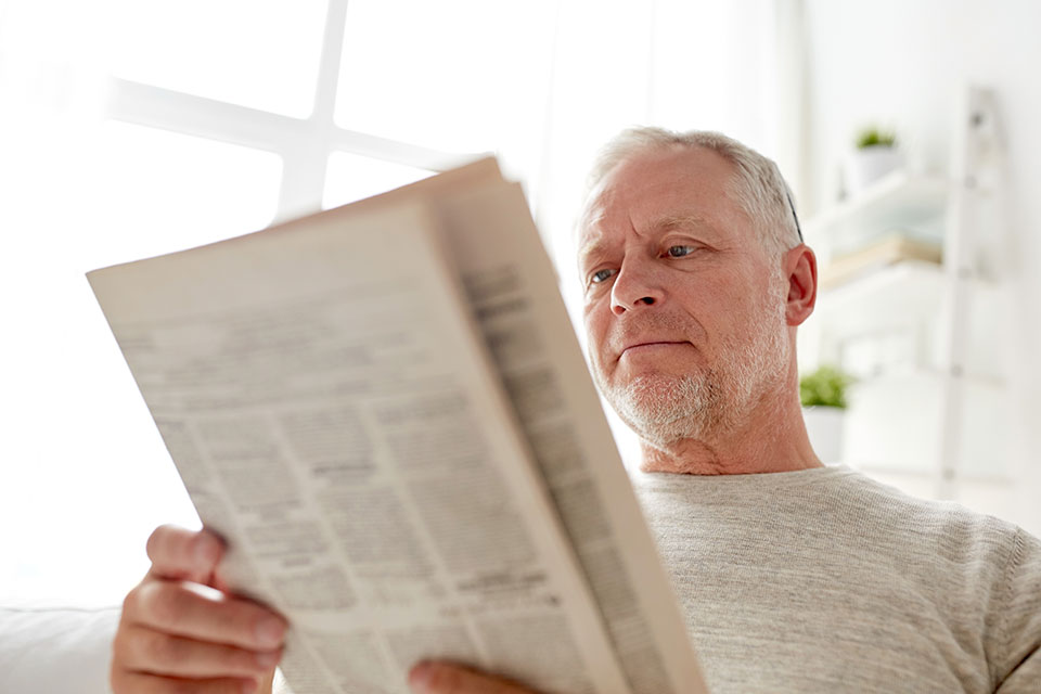 Älterer Mann hat Schwierigkeiten beim Lesen aufgrund der Alterssichtigkeit